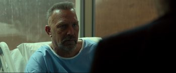 Movie still from “Criminal” (2016), directed by Ariel Vromen – An older man sitting in front of a mirror; Close Up shot, Over the shoulder angle