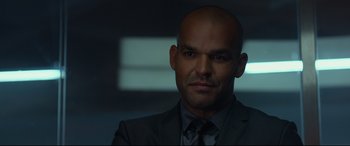 Movie still from “Criminal” (2016), directed by Ariel Vromen – A man in a suit and tie in a dark room; Close Up shot, Over the shoulder angle