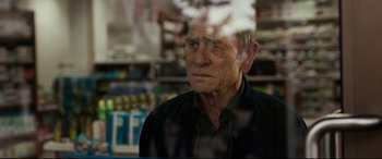Movie still from “Criminal” (2016), directed by Ariel Vromen – An older man looking out of a store window; Close Up shot, Over the shoulder angle