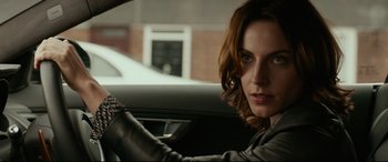 Movie still from “Criminal” (2016), directed by Ariel Vromen – A woman sitting in the driver's seat of a car; Close Up shot, Over the shoulder angle
