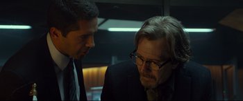 Movie still from “Criminal” (2016), directed by Ariel Vromen – A man in a suit and tie talking to another man in a suit and tie; Close Up shot, Over the shoulder angle