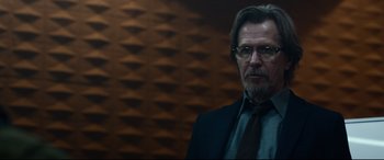 Movie still from “Criminal” (2016), directed by Ariel Vromen – A person wearing a suit and tie; Close Up shot, Over the shoulder angle