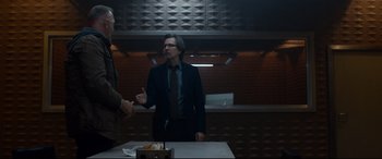 Movie still from “Criminal” (2016), directed by Ariel Vromen – Two men in suits are standing in a kitchen; Medium shot, Over the shoulder angle