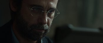 Movie still from “Criminal” (2016), directed by Ariel Vromen – A person wearing glasses and a beard; Close Up shot, Low angle