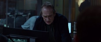 Movie still from “Criminal” (2016), directed by Ariel Vromen – An older man looking at a computer screen; Close Up shot, Over the shoulder angle
