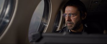 Movie still from “Criminal” (2016), directed by Ariel Vromen – A person wearing glasses in a plane; Close Up shot, Low angle