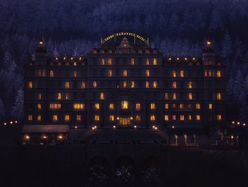 Movie still from “The Grand Budapest Hotel” (2014), directed by Wes Anderson – A large hotel lit up at night with lights on; Extreme Wide shot, Low angle
