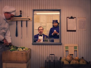 Movie still from “The Grand Budapest Hotel” (2014), directed by Wes Anderson – Two men are standing in front of a mirror; Medium shot, Over the shoulder angle