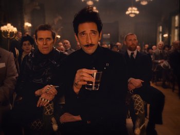 Movie still from “The Grand Budapest Hotel” (2014), directed by Wes Anderson – A group of people sitting in a room; Medium shot, Low angle