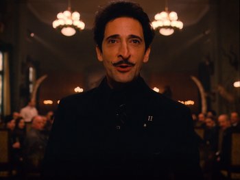 Movie still from “The Grand Budapest Hotel” (2014), directed by Wes Anderson – A man in a black jacket and a mustache; Close Up shot, Low angle