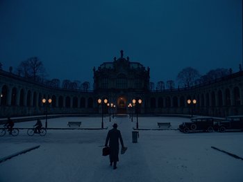 Movie still from “The Grand Budapest Hotel” (2014), directed by Wes Anderson – A man walking down a snow covered street at night; Extreme Wide shot, Low angle