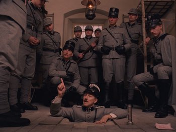 Movie still from “The Grand Budapest Hotel” (2014), directed by Wes Anderson – A group of men dressed in uniforms and hats; Wide shot, High angle