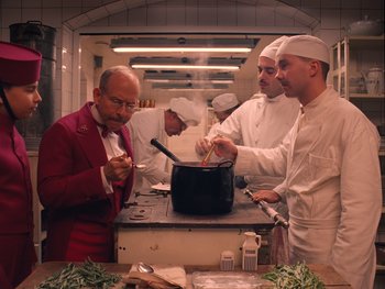 Movie still from “The Grand Budapest Hotel” (2014), directed by Wes Anderson – A group of men in a kitchen preparing food; Medium shot, Low angle