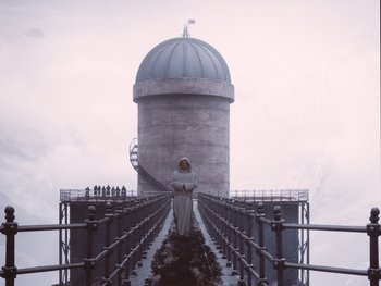 Movie still from “The Grand Budapest Hotel” (2014), directed by Wes Anderson – A man in a white robe standing on top of a bridge; Extreme Wide shot, Low angle