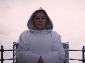 Movie still from “The Grand Budapest Hotel” (2014), directed by Wes Anderson – An old man wearing a white hooded sweatshirt; Medium shot, Low angle