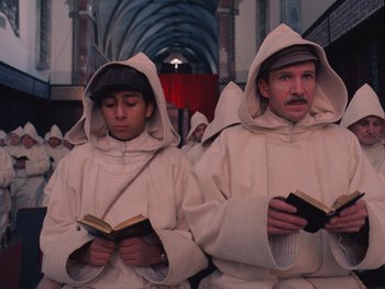 Movie still from “The Grand Budapest Hotel” (2014), directed by Wes Anderson – Two men dressed as monks are reading a book; Medium shot, Low angle