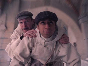 Movie still from “The Grand Budapest Hotel” (2014), directed by Wes Anderson – Two men are posing for a picture; Medium shot, Low angle