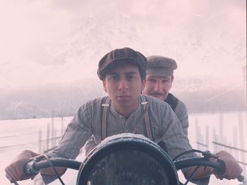 Movie still from “The Grand Budapest Hotel” (2014), directed by Wes Anderson – Two men are sitting on a bike in the water; Medium shot, Low angle