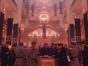 Movie still from “The Grand Budapest Hotel” (2014), directed by Wes Anderson – A group of people standing in a large room; Extreme Wide shot, Low angle