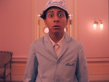 Movie still from “The Grand Budapest Hotel” (2014), directed by Wes Anderson – A man in a lab coat and a hat; Medium shot, Low angle