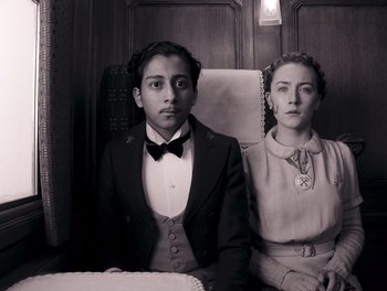 Movie still from “The Grand Budapest Hotel” (2014), directed by Wes Anderson – A man and a woman sitting in a chair; Medium shot, Overhead angle