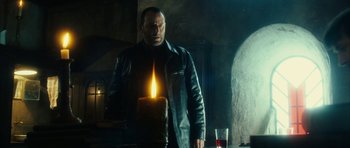 Movie still from “Crimson Rivers 2: Angels of the Apocalypse” (2004), directed by Olivier Dahan – A man standing in front of a lit candle; Medium shot, Low angle