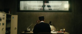 Movie still from “Crimson Rivers 2: Angels of the Apocalypse” (2004), directed by Olivier Dahan – A man sitting at a desk in front of a window; Wide shot, Over the shoulder angle