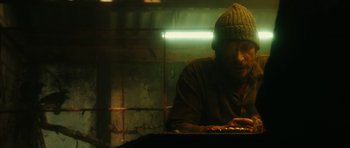 Movie still from “Crimson Rivers 2: Angels of the Apocalypse” (2004), directed by Olivier Dahan – A man wearing a hat is sitting at a table; Close Up shot, Low angle