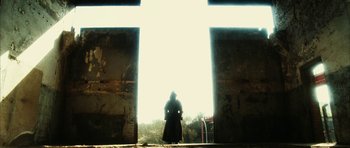 Movie still from “Crimson Rivers 2: Angels of the Apocalypse” (2004), directed by Olivier Dahan – A person standing in front of a large cross; Extreme Wide shot, Low angle