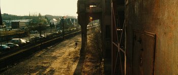 Movie still from “Crimson Rivers 2: Angels of the Apocalypse” (2004), directed by Olivier Dahan – A person walking down a dirt road near a train track; Extreme Wide shot, High angle