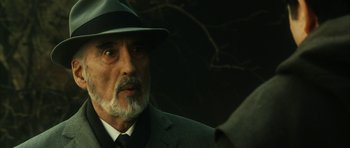 Movie still from “Crimson Rivers 2: Angels of the Apocalypse” (2004), directed by Olivier Dahan – An older man wearing a suit and a hat; Close Up shot, Over the shoulder angle
