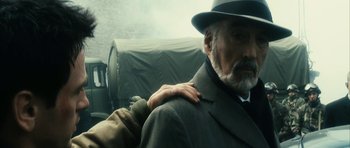 Movie still from “Crimson Rivers 2: Angels of the Apocalypse” (2004), directed by Olivier Dahan – An older man in a suit and hat with his hand on his shoulder; Close Up shot, Over the shoulder angle