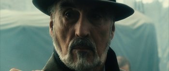 Movie still from “Crimson Rivers 2: Angels of the Apocalypse” (2004), directed by Olivier Dahan – An older man with a gray beard wearing a black hat; Close Up shot, Low angle