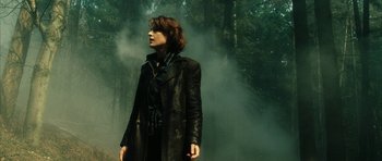 Movie still from “Crimson Rivers 2: Angels of the Apocalypse” (2004), directed by Olivier Dahan – A woman in a leather jacket standing in front of a forest; Medium shot, Low angle