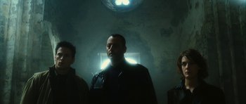 Movie still from “Crimson Rivers 2: Angels of the Apocalypse” (2004), directed by Olivier Dahan – A man standing in a room with a light shining on him; Medium shot, Low angle