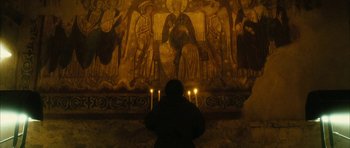 Movie still from “Crimson Rivers 2: Angels of the Apocalypse” (2004), directed by Olivier Dahan – A person standing in front of a painting with candles; Extreme Wide shot, High angle