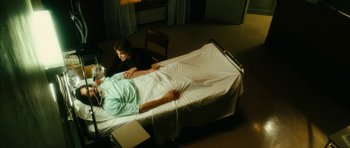 Movie still from “Crimson Rivers 2: Angels of the Apocalypse” (2004), directed by Olivier Dahan – A man laying in a hospital bed next to a woman; Medium shot, High angle