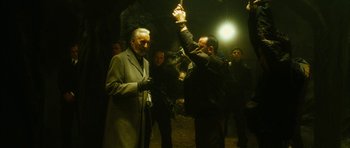 Movie still from “Crimson Rivers 2: Angels of the Apocalypse” (2004), directed by Olivier Dahan – A man holding up his hand while standing next to another man; Medium shot, Low angle