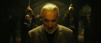 Movie still from “Crimson Rivers 2: Angels of the Apocalypse” (2004), directed by Olivier Dahan – An older man with a beard and a suit; Medium shot, Low angle