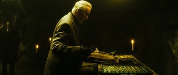 An old man in a suit is writing on a piece of paper
