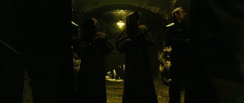 Movie still from “Crimson Rivers 2: Angels of the Apocalypse” (2004), directed by Olivier Dahan – A group of people in a cave holding guns; Wide shot, High angle