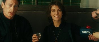 Movie still from “Crimson Rivers 2: Angels of the Apocalypse” (2004), directed by Olivier Dahan – A woman holding a glass of water and smiling; Close Up shot, Over the shoulder angle