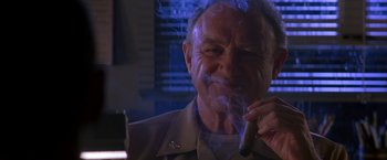 Movie still from “Crimson Tide” (1995), directed by Tony Scott – An older man smoking a cigar in a dark room; Close Up shot, Low angle