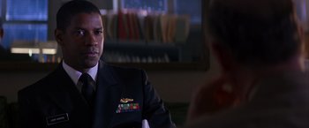 Movie still from “Crimson Tide” (1995), directed by Tony Scott – A man in a uniform sitting in front of another man; Close Up shot, Over the shoulder angle