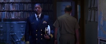 Movie still from “Crimson Tide” (1995), directed by Tony Scott – A man in a military uniform holding a hat in front of another man; Medium shot, Low angle