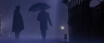 Movie still from “Crimson Tide” (1995), directed by Tony Scott – A man walking a dog in the rain with an umbrella; Wide shot, Low angle