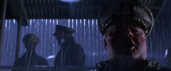 Movie still from “Crimson Tide” (1995), directed by Tony Scott – A man in a hat is standing in the rain next to another man in a hat; Close Up shot, Low angle