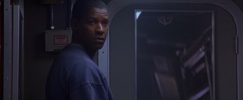 Movie still from “Crimson Tide” (1995), directed by Tony Scott – A man standing next to a door in a dark room; Close Up shot, Over the shoulder angle