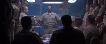 Movie still from “Crimson Tide” (1995), directed by Tony Scott – A man standing in front of a group of people; Medium shot, Low angle