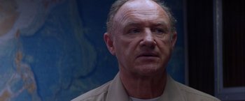 Movie still from “Crimson Tide” (1995), directed by Tony Scott – An older man in a tan shirt looking at the camera; Close Up shot, Low angle